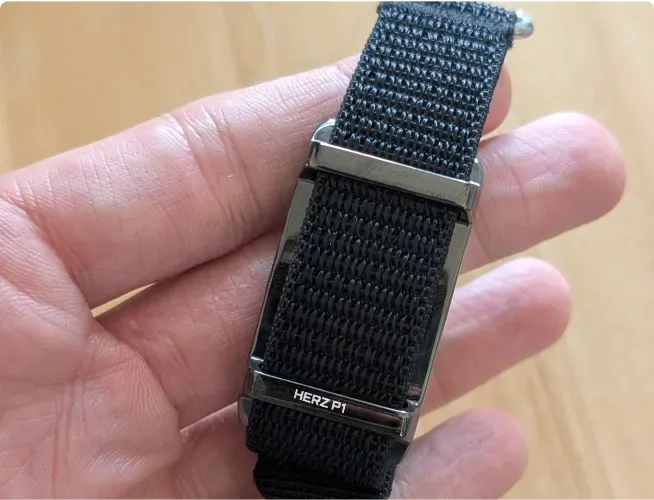 Herz P1 Smart Band sensor capsule and black nylon strap held in a hand