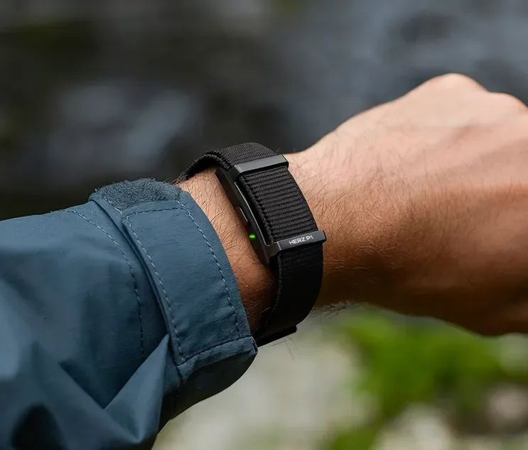 Herz P1 Smart Band worn on a wrist outdoors with the green optical heart rate sensor active